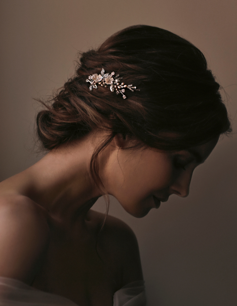 Side profile portrait of bride looking down. She has her hair up with a Tania Maras floral hair accessory pinned into the side of her braid.