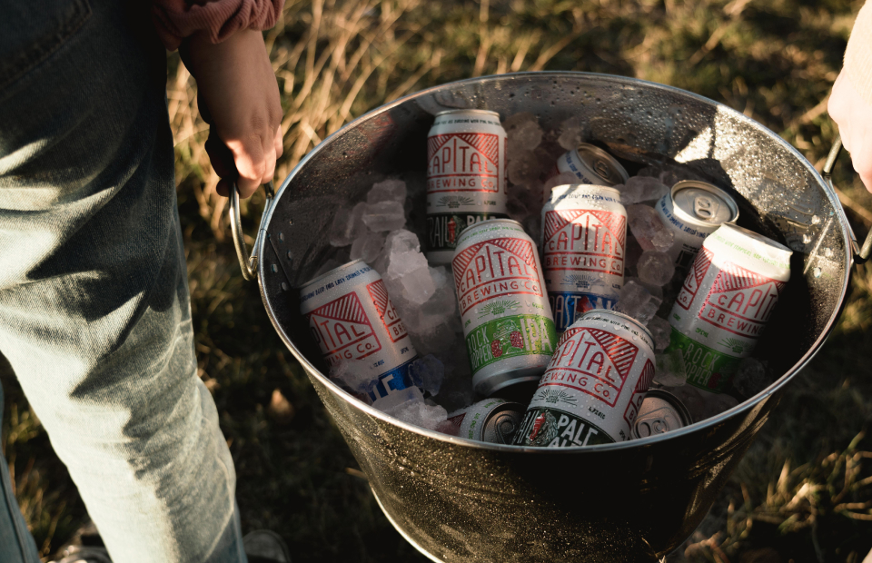 Hands holding a bucket full of beer cans and ice