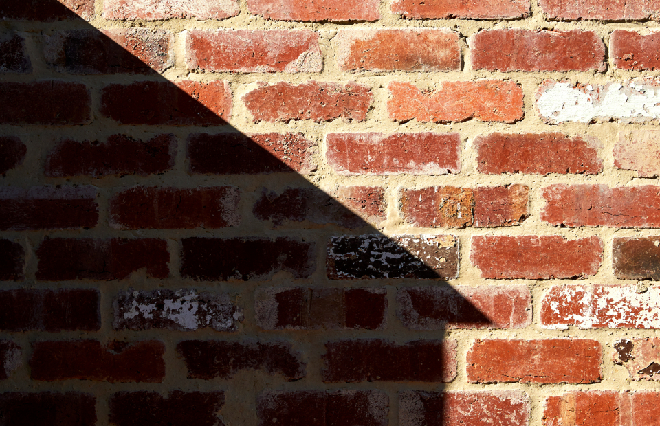 Shadow of building on brick wall.