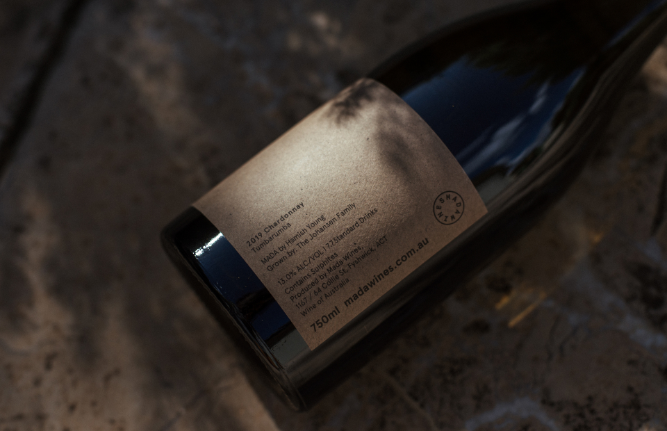 Close up of wine bottle label. Bottle is lying on its side, with shadows cast by trees.