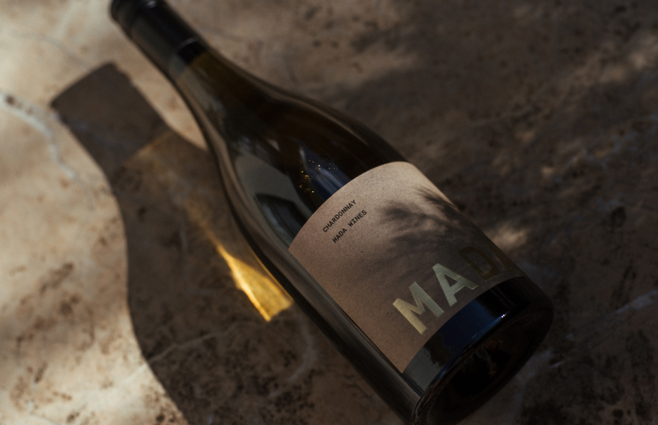 Close up of wine bottle label. Bottle is lying on its side, with shadows cast by trees.