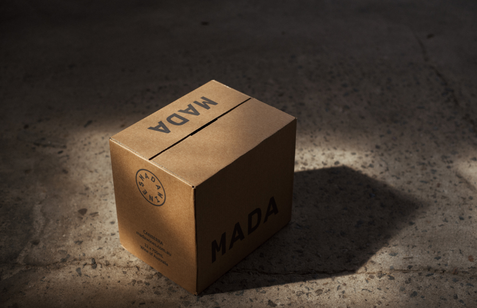 Mada wine box on concrete ground. Box is in a dark environment but has a soft spotlight shining on it.